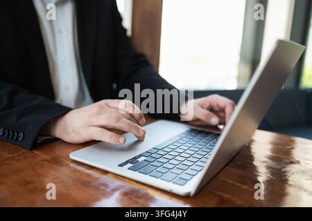 Mani di un uomo d'affari che usa un laptop su un tavolo di legno. Lavoro online, business digitale, produttività e concetto di tecnologia aziendale. Primo piano Foto Stock
