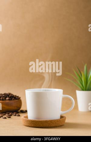 Caffè nero fumante in una tazza di ceramica bianca con chicchi e pianta Foto Stock