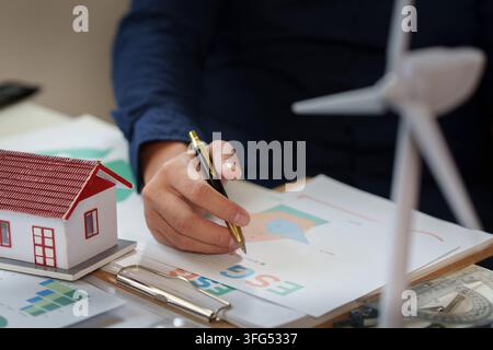 Mano ritagliata che punta una penna verso un documento di rapporto ESG per la consulenza energetica Foto Stock
