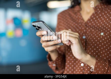 Donna che tiene e utilizza un moderno dispositivo di comunicazione mobile, digita un messaggio con le dita, impegnata nella comunicazione digitale e nella connettività Foto Stock