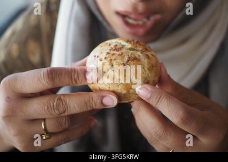Una donna si gode un prodotto appena sfornato mentre è seduta in un caffè. Foto Stock