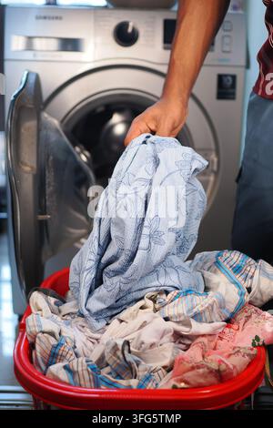 Persona che fa il bucato con i vestiti in un cesto Foto Stock