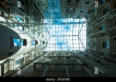 Prospettiva verticale a basso angolo che guarda direttamente verso l'alto di un atrio cortile architettonico moderno con un grande tetto in vetro trasparente e su Foto Stock