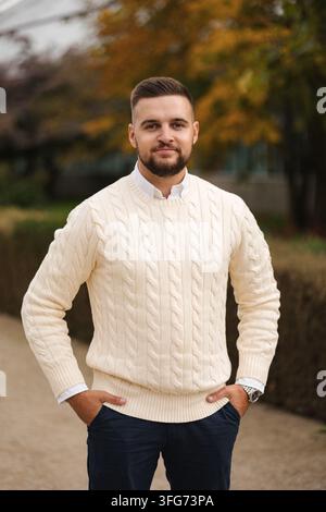 Prendersi un momento per rilassarsi all'aperto, un uomo vestito in modo casual si siede comodamente in un gilet elegante circondato dal fogliame autunnale. L'ambiente accogliente, naturale Foto Stock