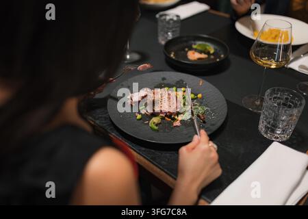 Donna che si gode il suo pasto gourmet in un ristorante di alta cucina con amici. Foto Stock
