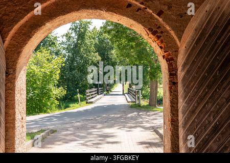 Vista panoramica di un ponte di legno attraverso un'antica arcata in pietra Foto Stock