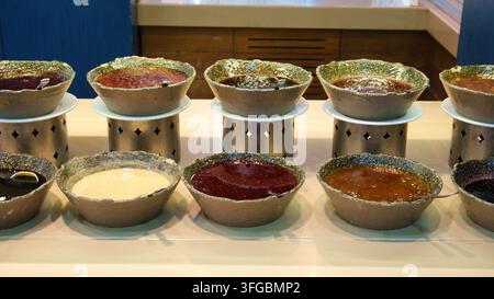 Un piano orizzontale di una linea di buffet per la colazione o il dessert di un hotel con varie salse, marmellate, miele e condimenti serviti in pietra decorativa rustica Foto Stock