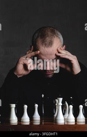 Uomo che gioca a scacchi su una scacchiera Foto Stock
