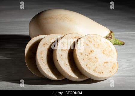melanzana bianca affettata su sfondo di legno grigio Foto Stock
