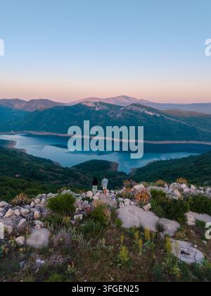 Una coppia si gode un momento sereno ammirando le splendide vedute del paesaggio montenegrino da Grancarevo. Le acque calme e la vegetazione lussureggiante creano Foto Stock