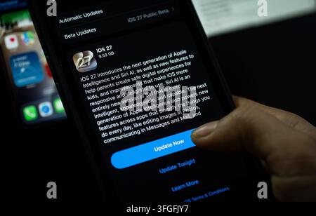 In questa illustrazione fotografica, una persona preme il pulsante "Aggiorna ora" su un iPhone che mostra lo schermo dell'aggiornamento software iOS 27, evidenziando l'ultima novità di Apple Foto Stock