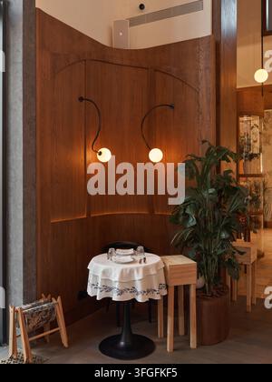 Un angolo pranzo accogliente con un muro di legno e pannellatura curva, che crea un'atmosfera rilassata e invitante. Da una vista dall'alto, il tavolo con un bianco Foto Stock