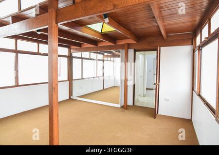 Interno di uno spazio loft con travi in legno e pavimento moquetteato: Un'ampia area loft con travi in legno a vista, un pavimento moquetteato e una grande finestra Foto Stock