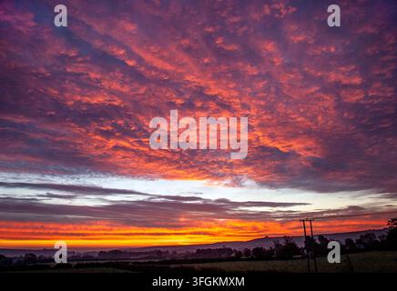 Tramonto su Wingreen Hill nel Dorset, UK, con nuvole arancioni infuocate che brillano sopra la campagna ondulata Foto Stock