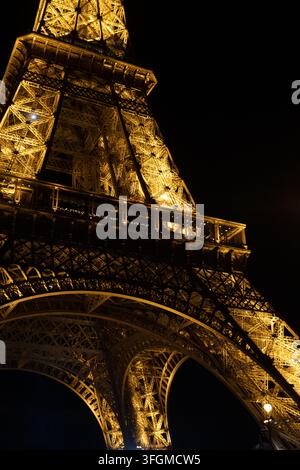 Torre Eiffel illuminata di notte vista dal basso contro un cielo nero a Parigi, Francia Foto Stock