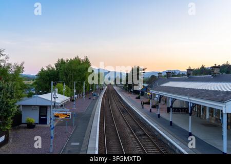 Kingussie Scozia - 30 maggio 2023: La stazione ferroviaria di Kingussie in Scozia con persone in attesa sul binario al tramonto Foto Stock
