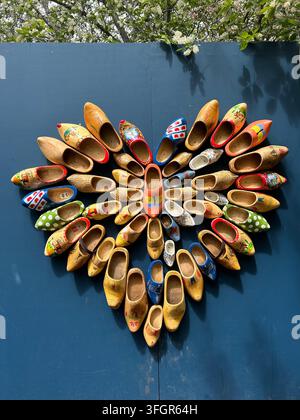 Sabotti di legno colorati disposti a forma di cuore su un muro blu Foto Stock