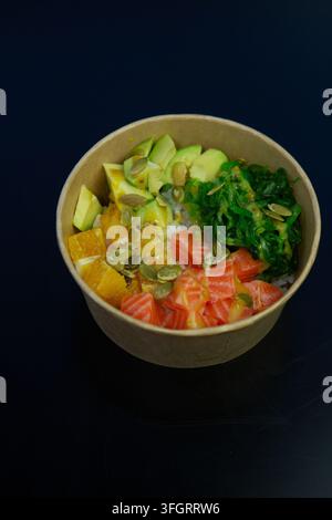 Una ciotola contiene un mix di ingredienti freschi tra cui diversi tipi di verdure e frutta. L'insalata è arricchita da alghe verdi e semi in superficie. Foto Stock