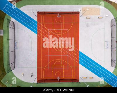 Vista aerea di un moderno campo sportivo multiuso con un'area di basket rossa e una pista da corsa blu a Danzica, Polonia. Foto Stock