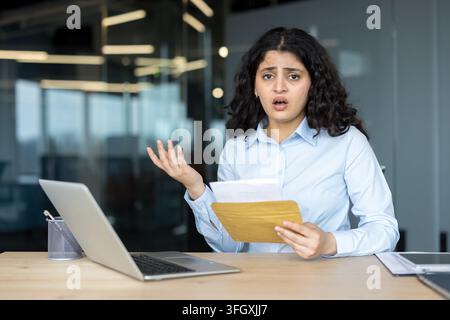 Donna d'affari stressata con laptop e documenti in ufficio. Foto Stock