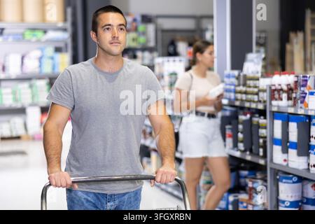 Uomo che fa acquisti in un negozio di materiali edili, spinge un carrello Foto Stock
