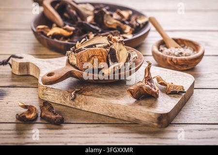 Funghi di bosco essiccati in cucchiai e ciotole di legno su un tavolo rustico Foto Stock