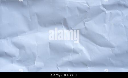 Sfondo in texture di carta bianca accartocciata con superficie piegata, inquadratura astratta a tutto campo, primo piano, vista dall'alto come elemento di design. Foto Stock
