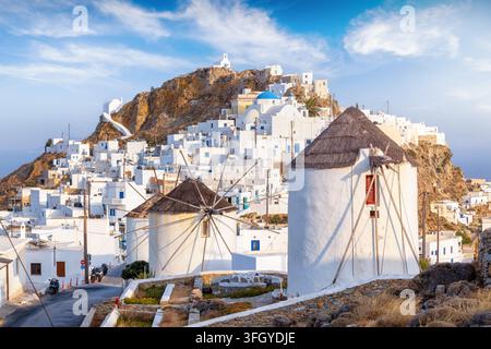 La bellissima città dell'isola di Serifos, Cicladi, Grecia, con case imbiancate a calce e mulini a vento su una montagna durante il tramonto estivo Foto Stock