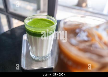 Latte matcha a strati con tè matcha verde brillante su latte freddo servito in un bicchiere in un caffè moderno in Thailandia. Bevanda asiatica di tendenza, cultura del caffè Foto Stock