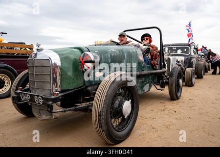Hot rod vintage sulla spiaggia sud di Bridlington durante la Race to the Waves 2026, East Yorkshire, con la bandiera Union Jack che sventola Foto Stock
