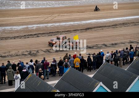 Pick-up vintage rat rod e moto sulla spiaggia sud di Bridlington durante la Race to the Waves 2026, osservati da folle di persone Foto Stock