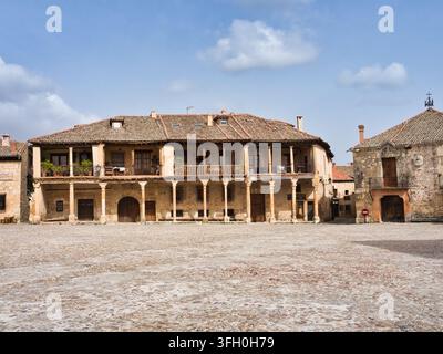 Edificio storico della piazza del villaggio spagnolo – Edificio tradizionale in pietra e legno con balconi che si affacciano su una larga piazza lastricata in un incantevole Spagna Foto Stock
