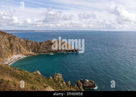 Una scena costiera aspra con scogliere ripide che si tuffano in acque blu profonde, catturata durante l'ora blu. Foto Stock