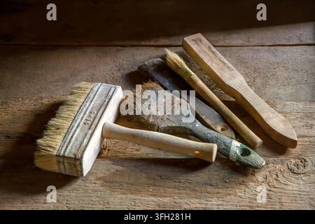 Vecchi pennelli su uno scaffale di legno. Vecchi pennelli per dipingere su superfici di legno ruvide. Foto Stock