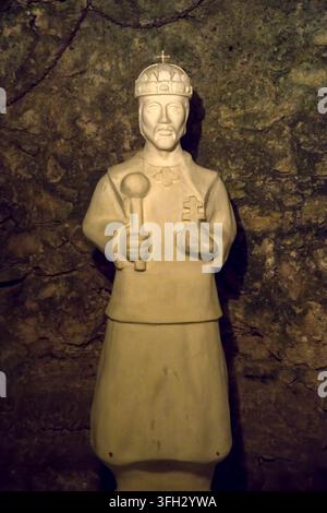Statua di Santo Stefano I d'Ungheria che raffigura il re con uno scettro e una sfera con una croce, in piedi su uno sfondo di parete rocciosa di grotta ruvida in Foto Stock
