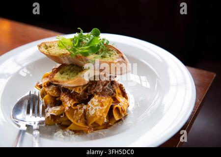 Pasta tagliatelle condita con carne saporita, verdure fresche e pane croccante invita all'indulgenza. Foto Stock