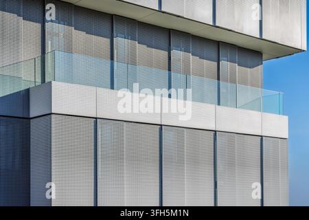 Facciata di edificio moderno con pannelli metallici perforati e ringhiera del balcone in vetro Foto Stock