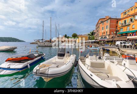 Edifici colorati sul lungomare, caffè e barche ormeggiate costeggiano il porto della vecchia città di Villefranche-sur-Mer sulla costa della Costa Azzurra nel sud di Fra Foto Stock
