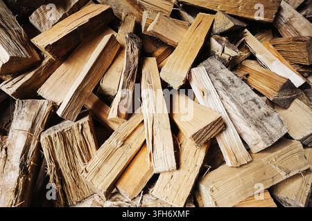 Legna da ardere spezzata impilata in un grande mucchio all'aperto. Sfondo in legno naturale per combustibile da riscaldamento, energia per caminetto, preparazione invernale e vita rurale. Foto Stock