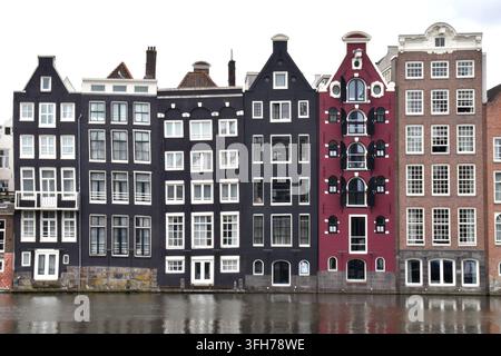 Case di mercanti del XVII secolo sul lungofiume del Damrak ad Amsterdam all'interno della fila di case inclinate e pendenti conosciute come le Case Danzanti del Damrak. Foto Stock