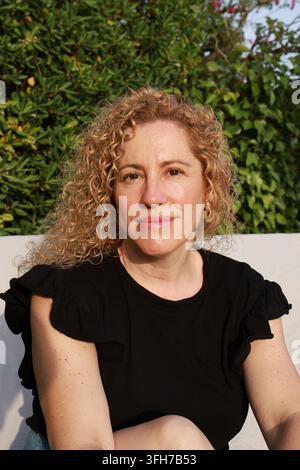 Ritratto di una bella donna bionda di mezza età con capelli ricci Foto Stock