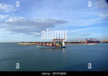 VALENCIA, SPAGNA - 21 OTT 2025 - Nave portacontainer carica di container colorati che naviga attraverso il porto di Valencia, mostrando la logistica del commercio globale moderno Foto Stock