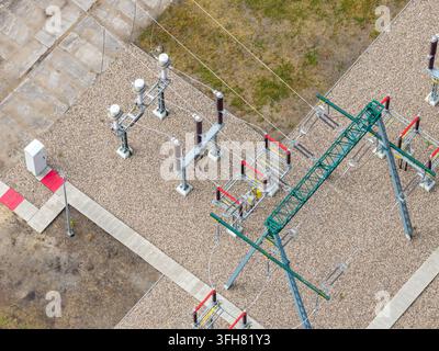 Vista aerea di una sottostazione elettrica con apparecchiature ad alta tensione, strutture metalliche e terreno in ghiaia in Polonia. Foto Stock