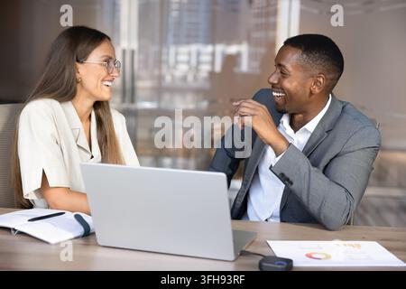 Colleghi multietnici allegri che discutono di un progetto durante una riunione professionale di affari Foto Stock