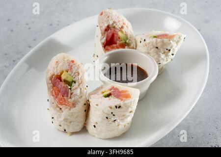 Una vista di un rotolo di sushi, con salmone, tonno e avocado. Foto Stock