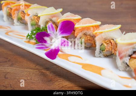 Una vista di un rotolo di sushi con salmone al forno, salmone crudo e branzino crudo. Foto Stock