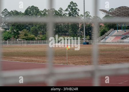 Vista attraverso una griglia bianca sfocata di un campo da stadio sportivo con una bandiera d'angolo e una pista di atletica leggera. Foto Stock