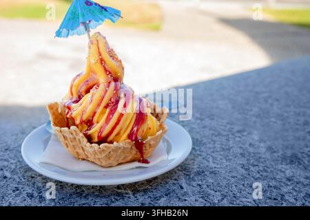 Gelato morbido al mango colorato con salsa ai frutti di bosco in ciotola di waffle Foto Stock