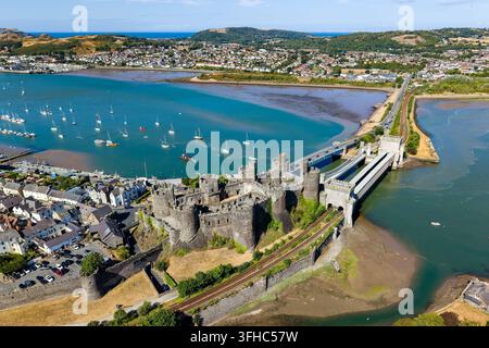 Vista aerea del castello di Conwy e dei ponti storici che attraversano il fiume Conwy nel nord del Galles, con barche ormeggiate sull'acqua blu dell'estuario, in una giornata estiva Foto Stock