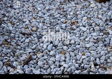 Vista a tutto campo di varie piccole pietre grigie e bianche che formano una superficie di ghiaia densa e grezza, perfetta per progetti di costruzione, percorsi o cortili rustici Foto Stock